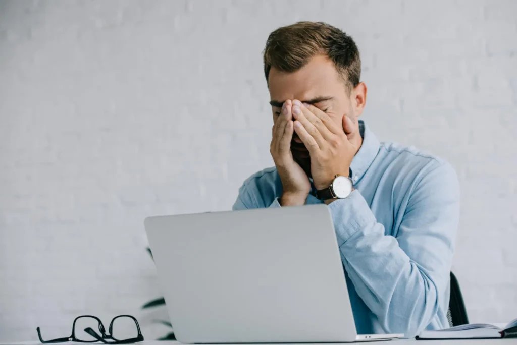Red Eyes Causes: Why Your Eyes Turn Red and What to Do About It young businessman suffering from pain in eyes while working with laptop